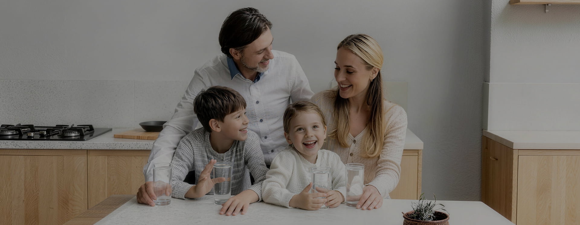 Smiling family drinking fresh water filtered by an Electrolux home water purification system.